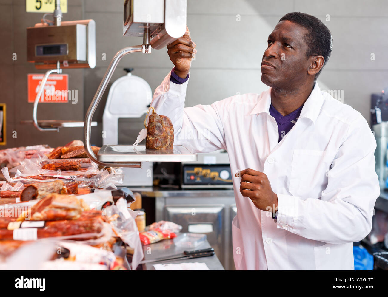 Zuversichtlich Afrikanische amerikanische Verkäufer wiegen Jamon auf Skala in Metzgerei Stockfoto