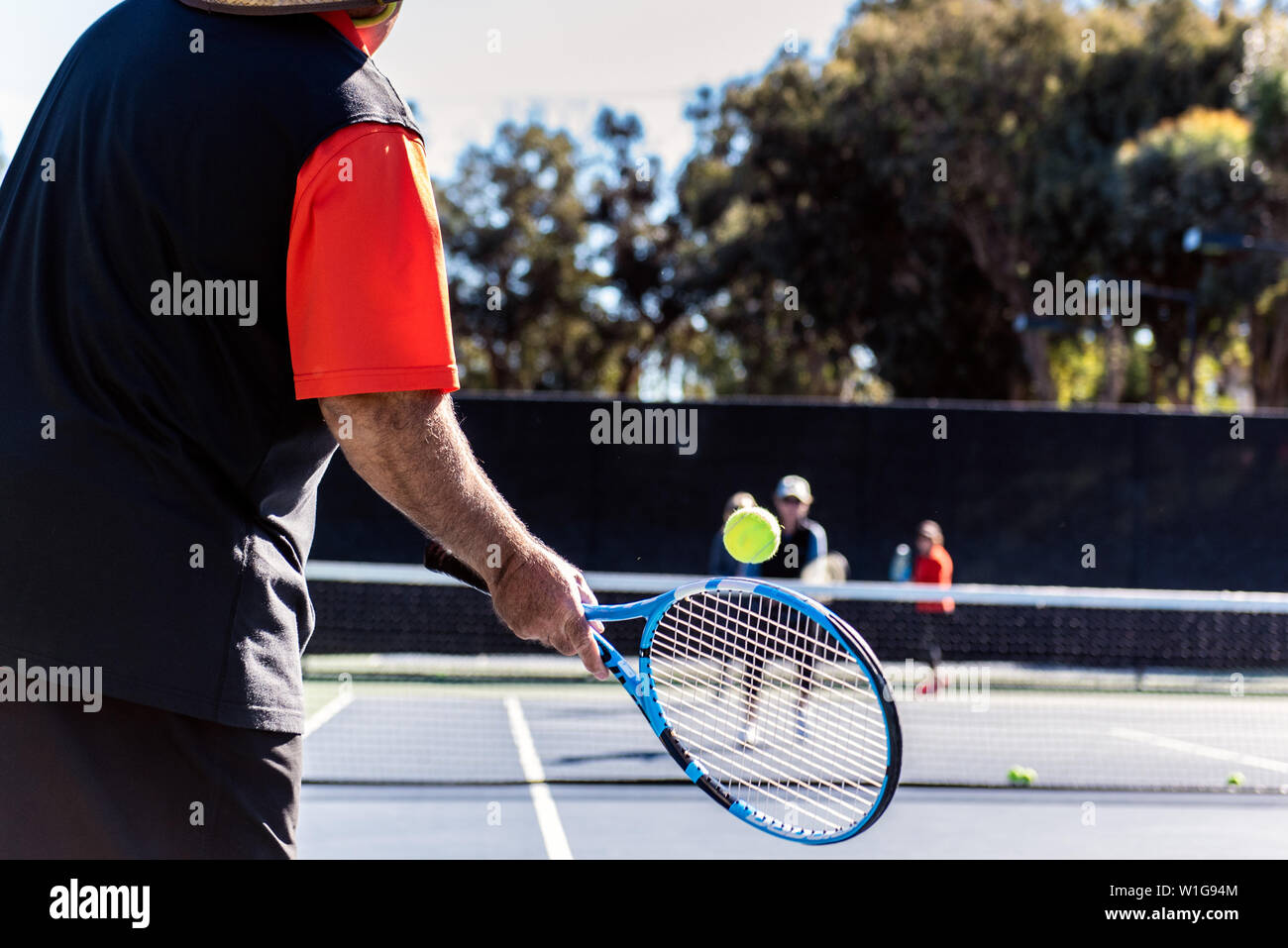 Tennis pro Fütterung Kugeln Lektion Teilnehmer Gruppe während teachng wie eine gute Vorhand über das Netz zu schlagen. Stockfoto