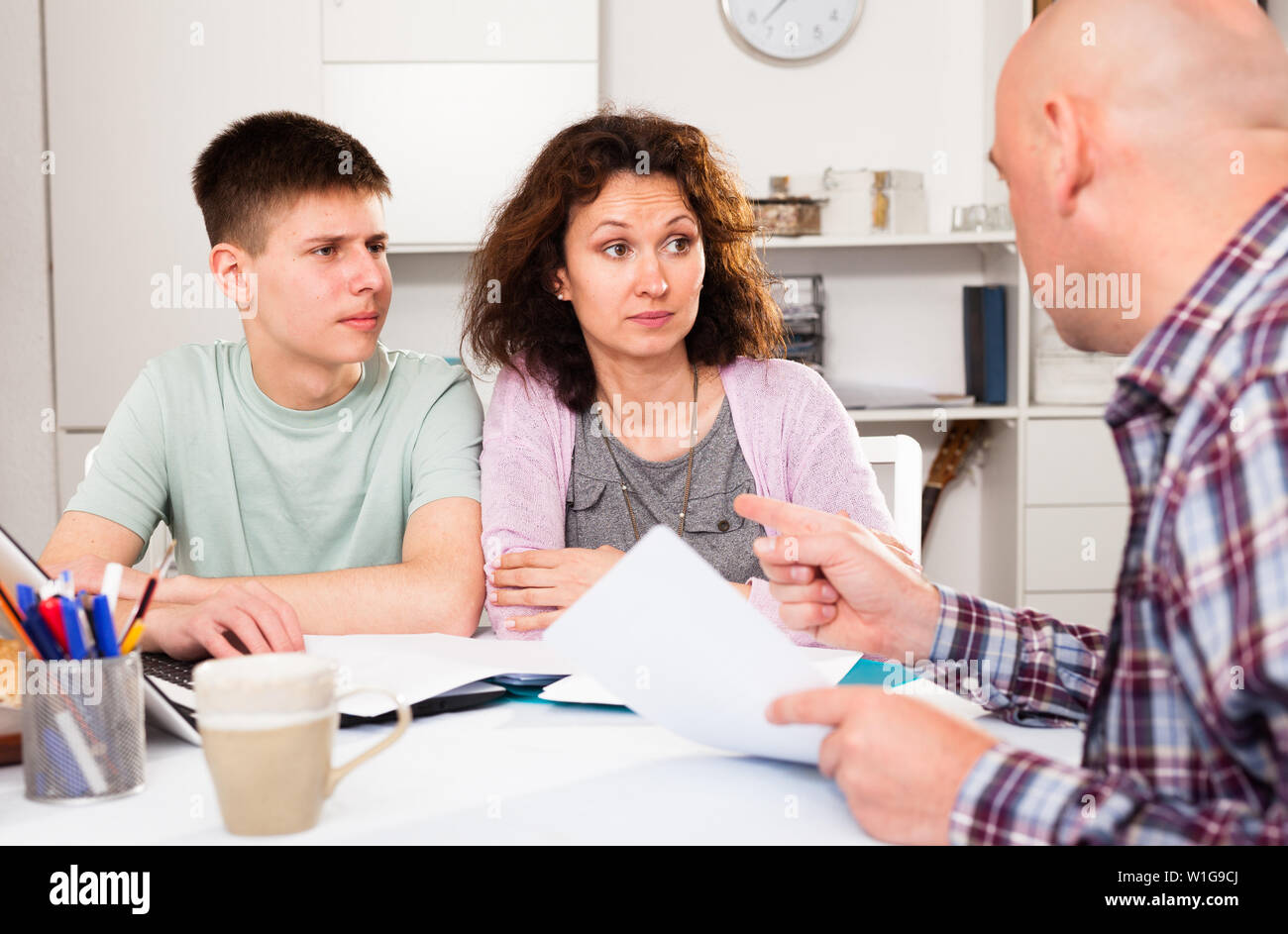 Junger Mann mit seiner Frau und seinen jüngeren Sohn Lesen von Dokumenten zu Hause Tabelle Stockfoto