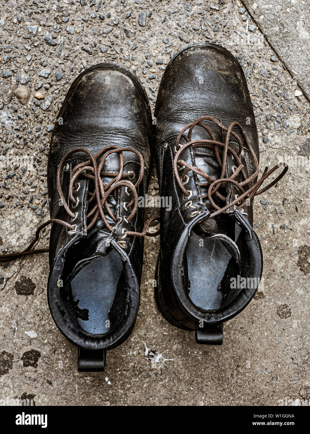 Alt, abgenutzt, schwarze spitze Schuhe auf einem Bürgersteig Stockfoto