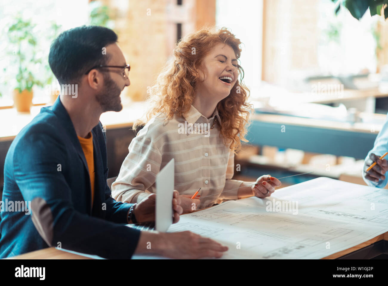 Frau lachend. Schöne lockige rothaarige Frau lachend, während Zusammen mit Kollegen Stockfoto