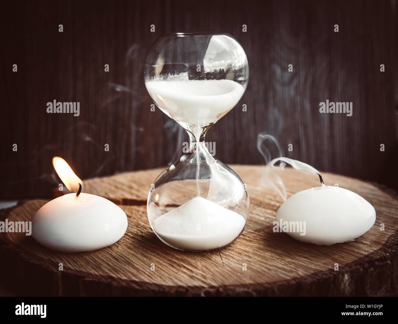 Die Zeit wird knapp, Leben und Tod. Eine Kerze brennen mit Flamme wie andere Leben wird als tot und Sanduhr Maßnahmen Lebenszeit geblasen. Stockfoto