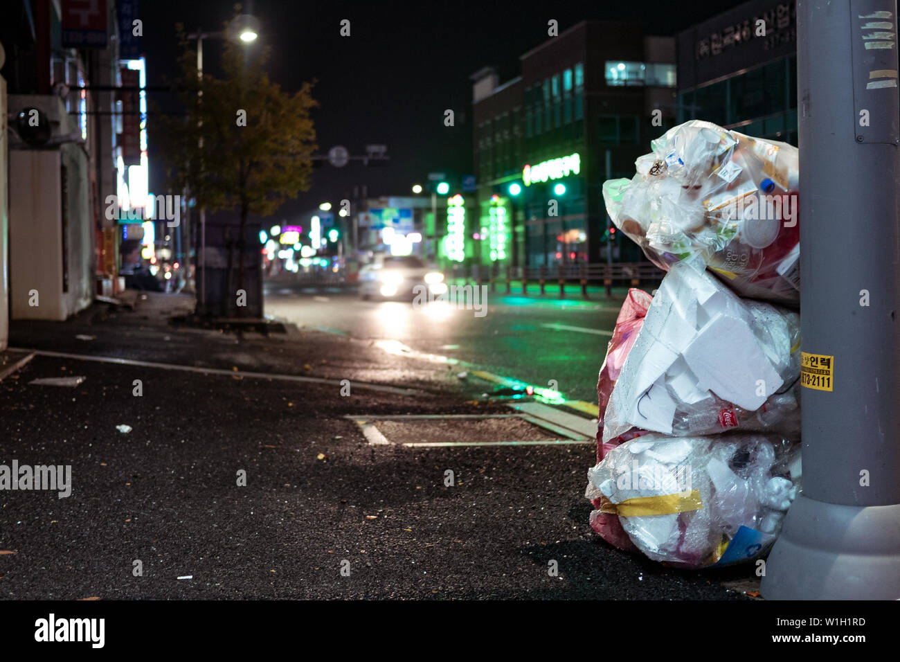 Seoul, Südkorea - 30.10.18: Säcke mit Müll liegen auf der Seite der Straße bei Nacht. Ein Haufen Müll auf die Straße geworfen. Neonlicht. Umwelt p Stockfoto