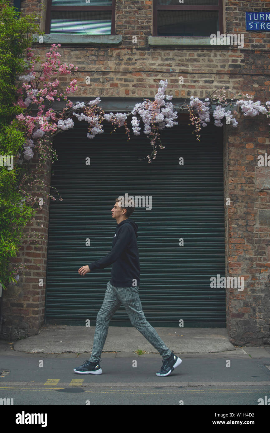 Mann Anfang 30 das Laufen auf den Straßen von Manchester Vergangenheit ein buntes Graffiti an der Wand. Stockfoto