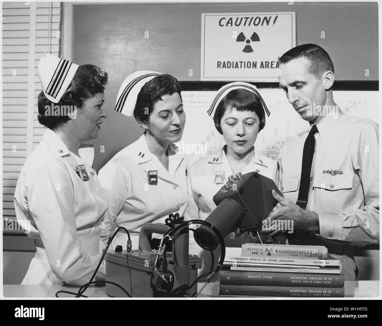 Nukleare Pflegeversicherung Chief Hospitalman Lee Jones, US Navy, Silver Spring, Maryland, zeigt Strahlung Umfrage Instrumente verwendet, um das Vorhandensein von Radioaktivität zu messen, als Teil des nuklearen Krankenpflege Kurs an der National Naval Medical Center, Bethesda, Maryland. Die Krankenschwestern von links nach rechts sind: Lieutenant Commander Anne prüfen, Perth Amboy, New Jersey; Leutnant Margaret M. Smith, Riverdale, New York, und Leutnant Lina D. Murasheff, Richmond, Kalifornien Stockfoto