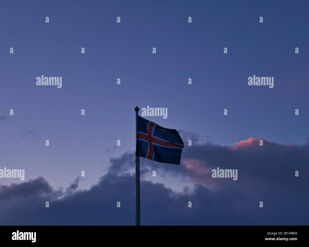 Isländischer Flagge am Abend mit bunten Wolken im Hintergrund Stockfoto