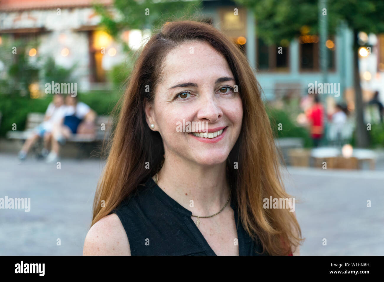 Porträt einer reifen Frau, 40s, Lächeln suchen Kamera draußen in einer Stadt. Stockfoto