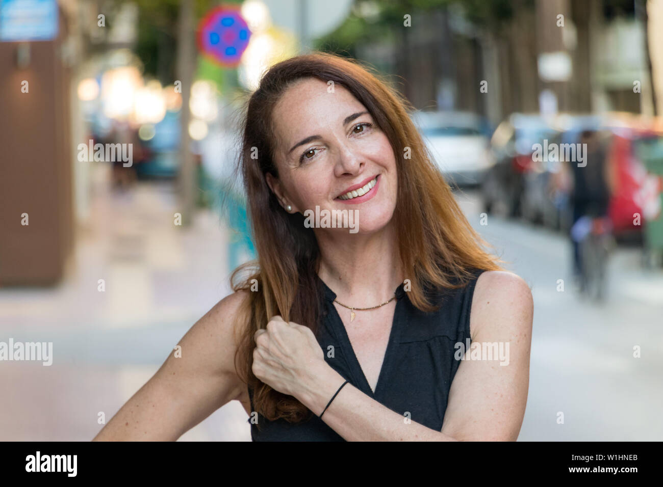 Porträt einer reifen Frau, 40s, Lächeln suchen Kamera draußen in einer Stadt. Stockfoto