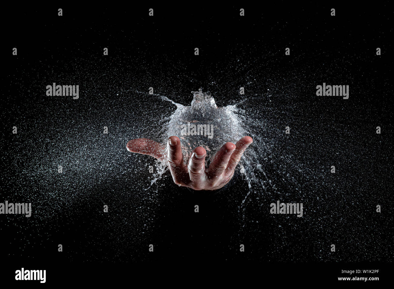 Explosion eines Ballon voll Wasser auf einer Hand gehalten, schwarzer Hintergrund Studio gedreht. Hi Speed Fotografie Stockfoto