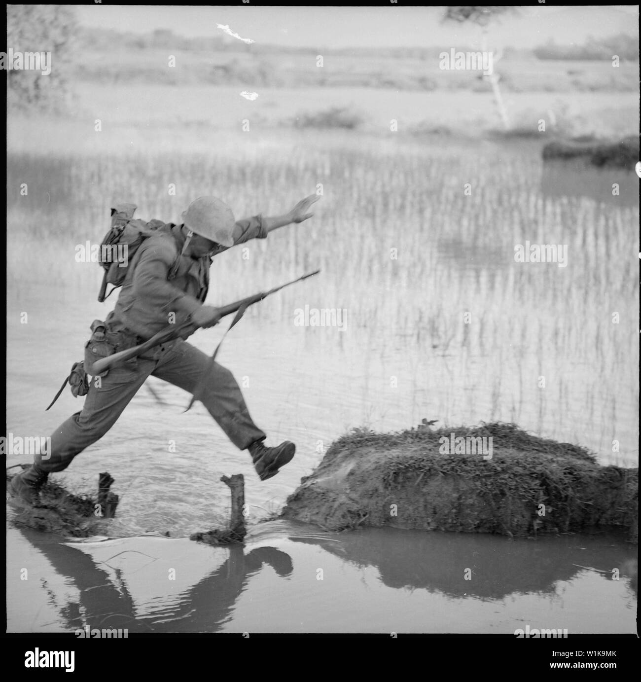 Vietnam .... ein Marine rifleman mit Firma H, 2nd Battalion, 5th Marines, Sprünge über eine Pause in einem Reisfeld Deich während einer Suchen und Zerstören mission auf Betrieb Colorado. Stockfoto