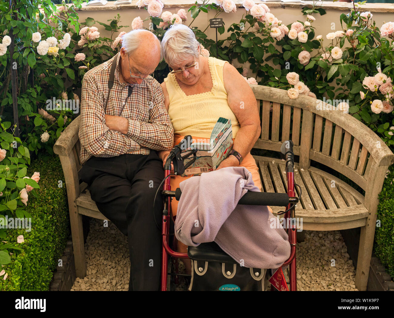 Senior Paar schlafen auf einer Bank von Rosen umgeben, an der RHS Hampton Court Palace Garden Festival. Stockfoto