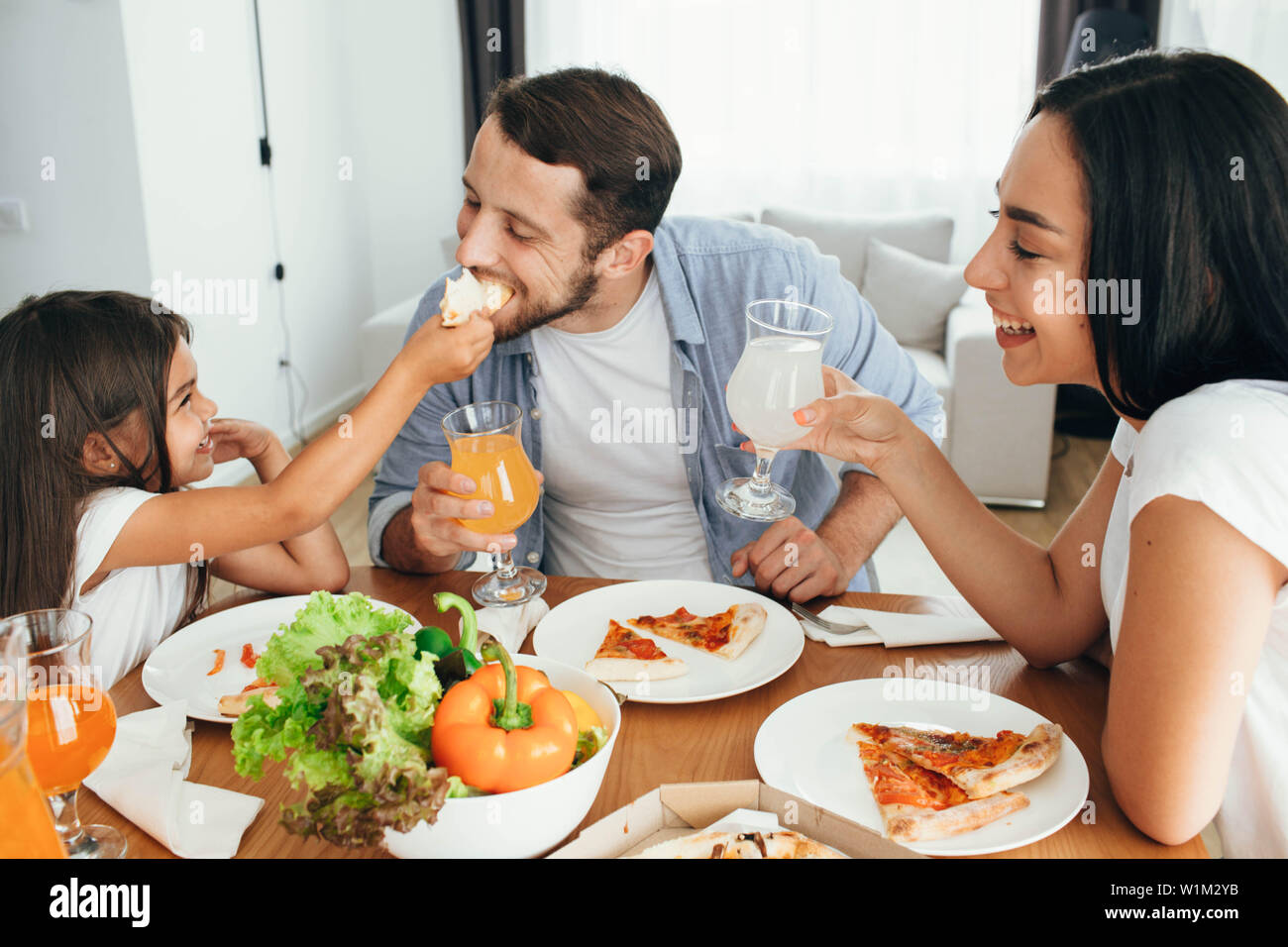 Familie Pizza. Vater, Mutter und Tochter beim Abendessen. Yammy, es ist sehr lecker Stück Pizza Stockfoto