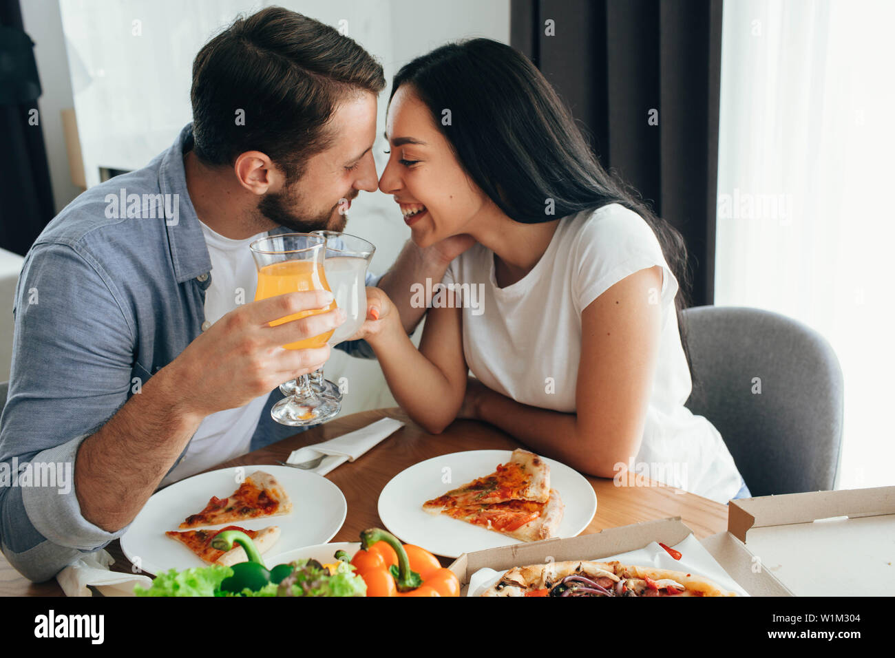 Glückliches Paar küssen und ein Abendessen mit Pizza zu Hause. Es ist eine gute Zeit verbringen Home Stockfoto