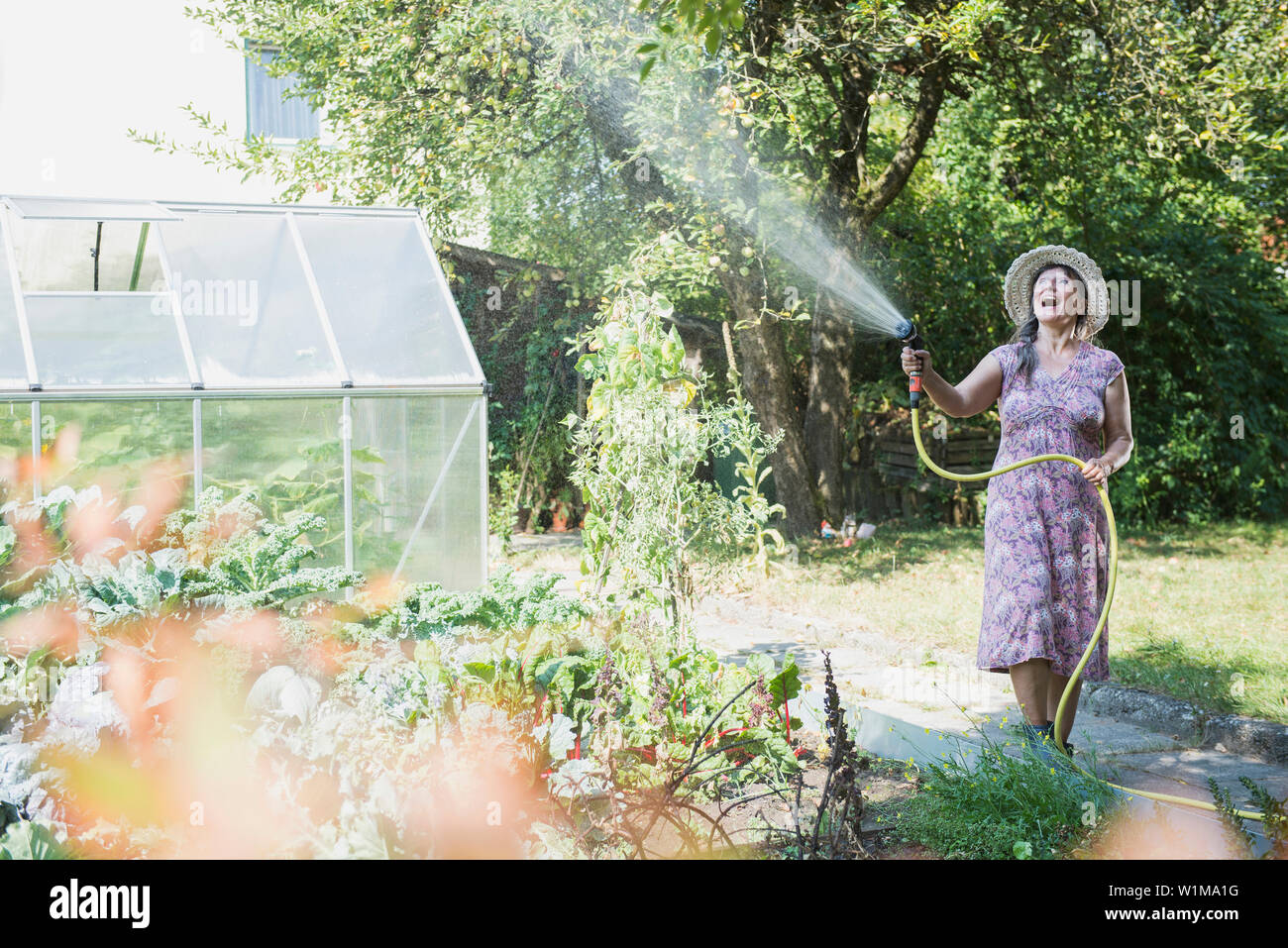 Ältere Frau, Bewässerung von Pflanzen im Garten, Altötting, Bayern, Deutschland Stockfoto