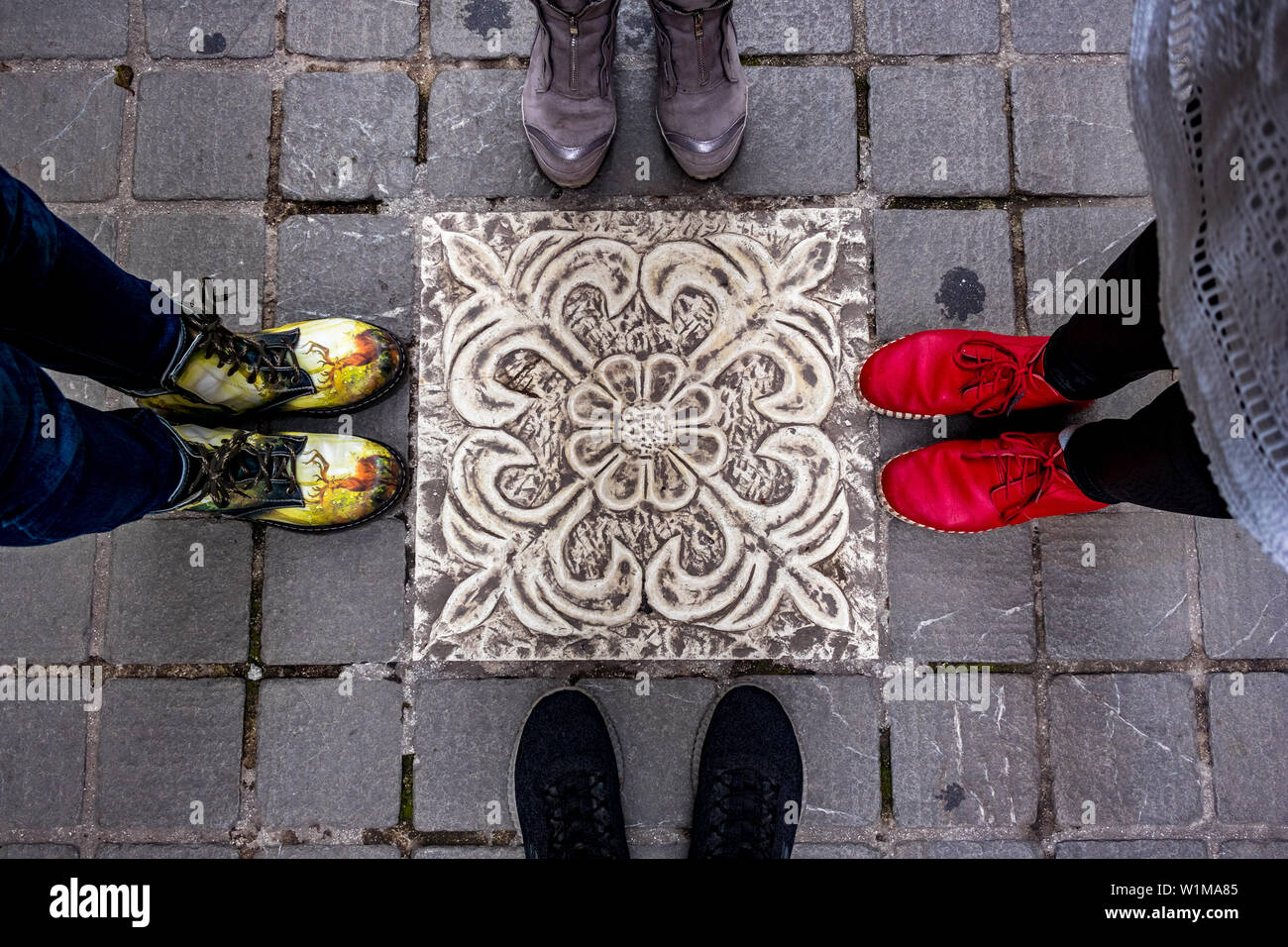 IOANNINA, Griechenland - Juni 6, 2019 - 4 Paar bunte Schuhe von Menschen rund um schöne Terrasse, Fliese, stehen im Zentrum der kleinen schönen Altstadt Stockfoto