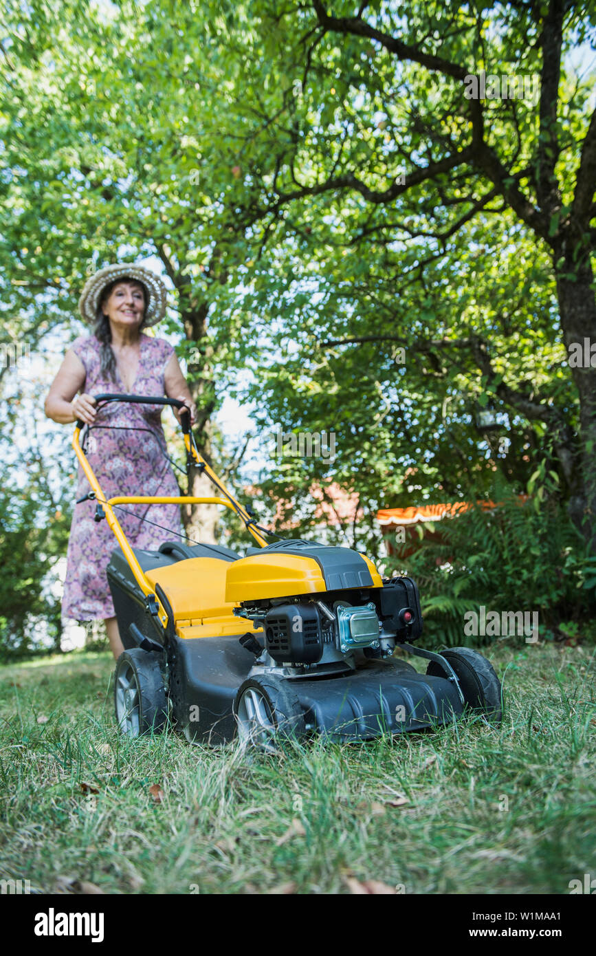 Ältere Frau mähen den Rasen im Garten, Altötting, Bayern, Deutschland