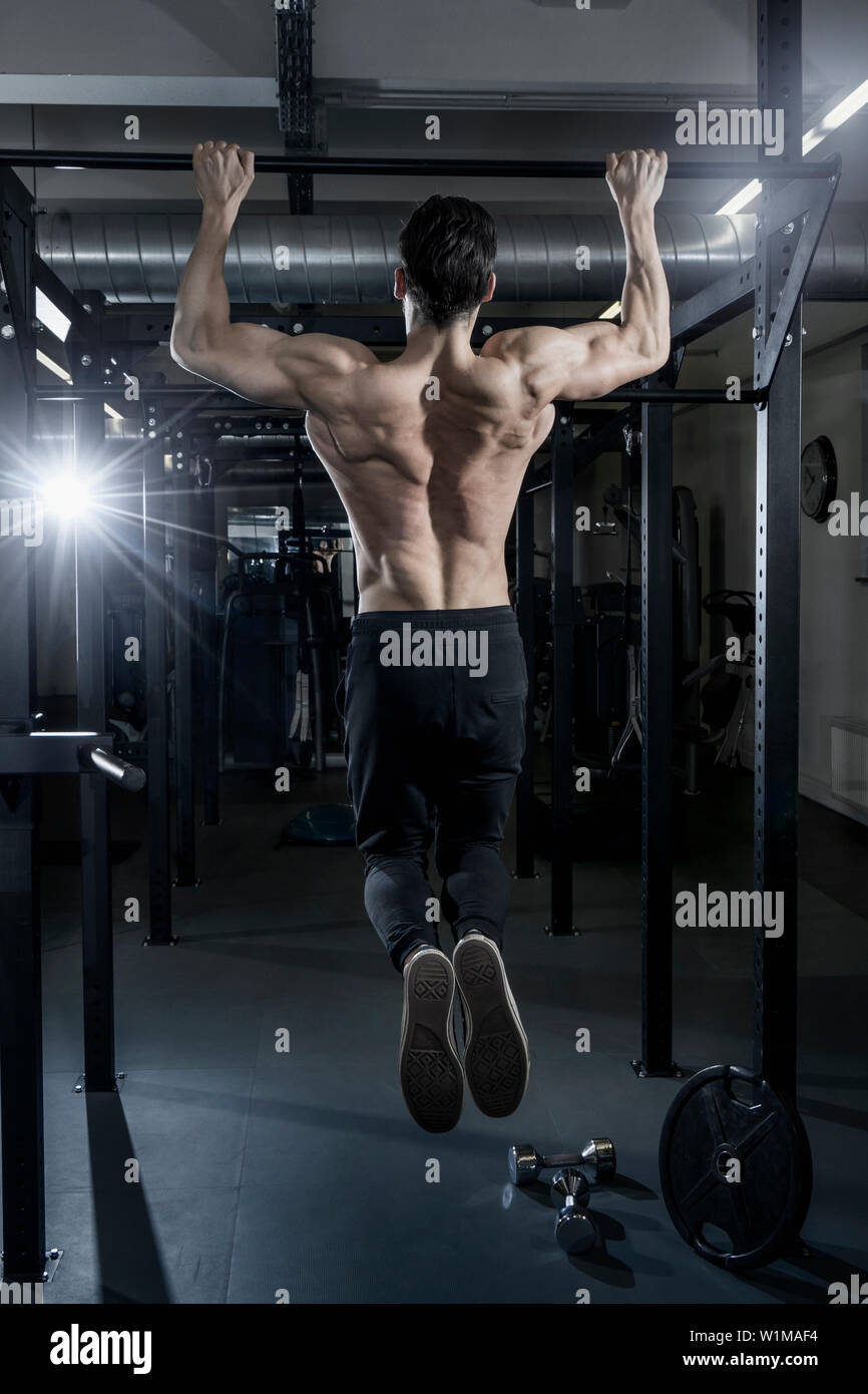 Shirtless muskulösen Mann tun Klimmzüge trainieren Sie im Fitnessraum Stockfoto