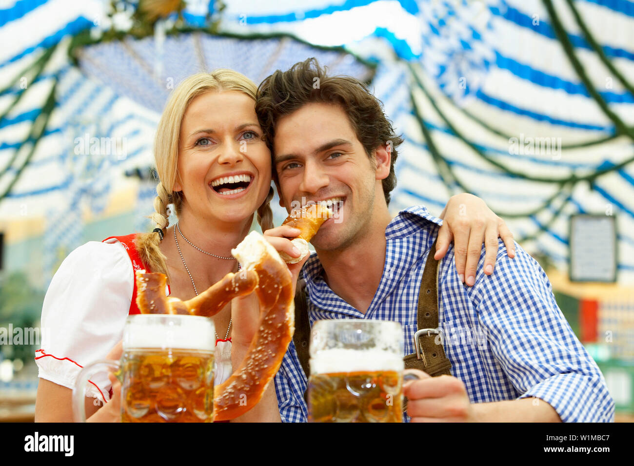 Paar mit Bier und Brezel in einem Bierzelt Stockfoto