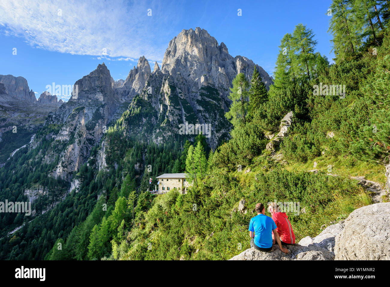 Zwei Personen, die Wandern sitzt auf Felsen vor der Hütte Rifugio Treviso mit Cima dei Lastei, das Tal Val Canali, Pala, Dolomiten, UNESCO-Herita Stockfoto