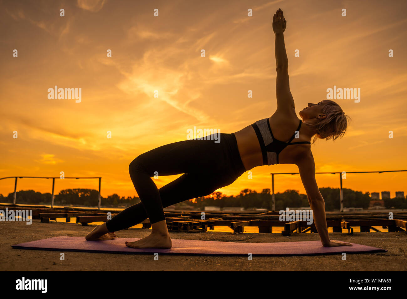 Frau Training Pilates in den Sonnenuntergang. Seitlicher Ganzkörperstütz Übung. Stockfoto