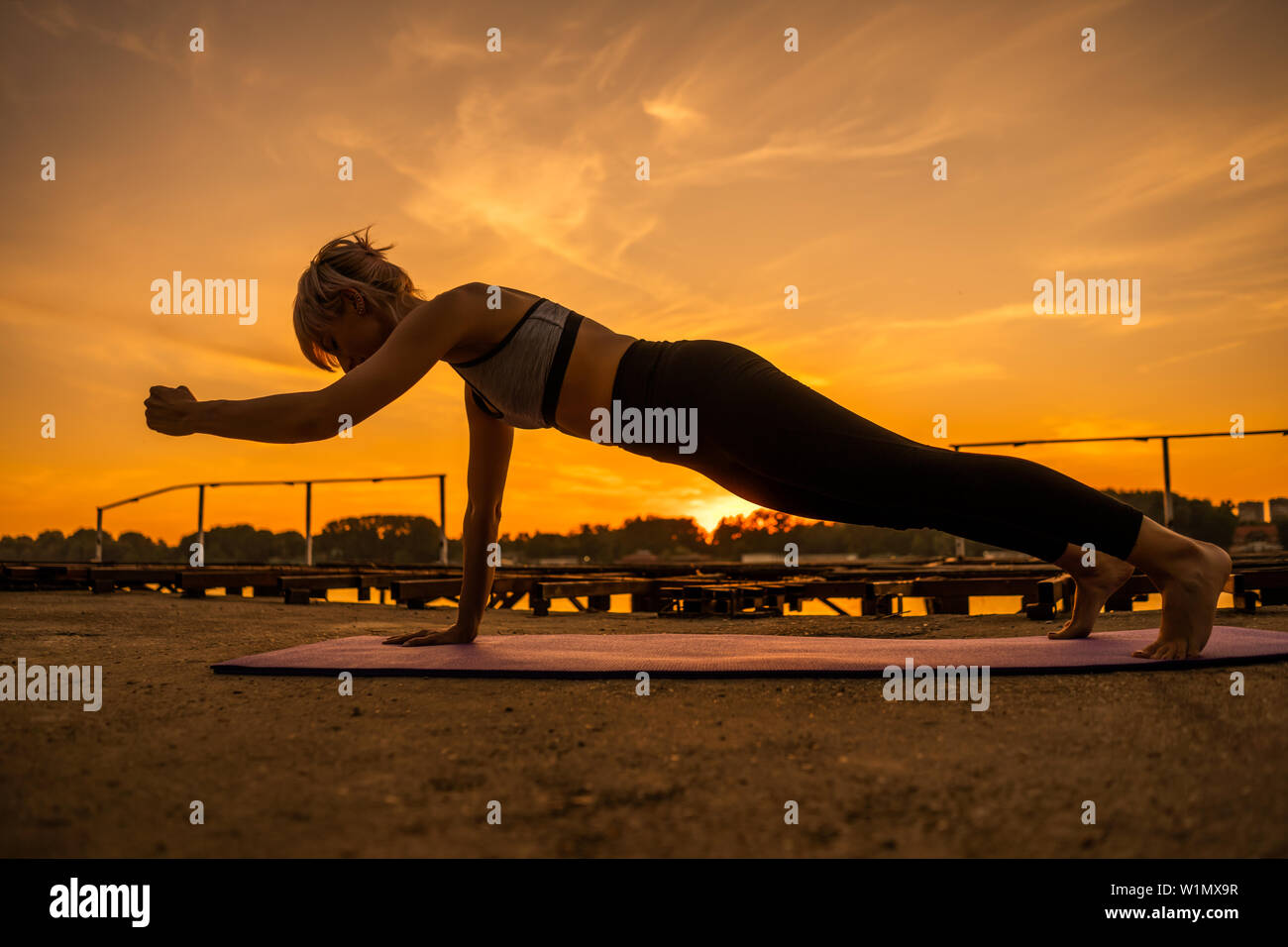 Frau Training Pilates in den Sonnenuntergang. Ein arm Damen Push up Übung. Stockfoto