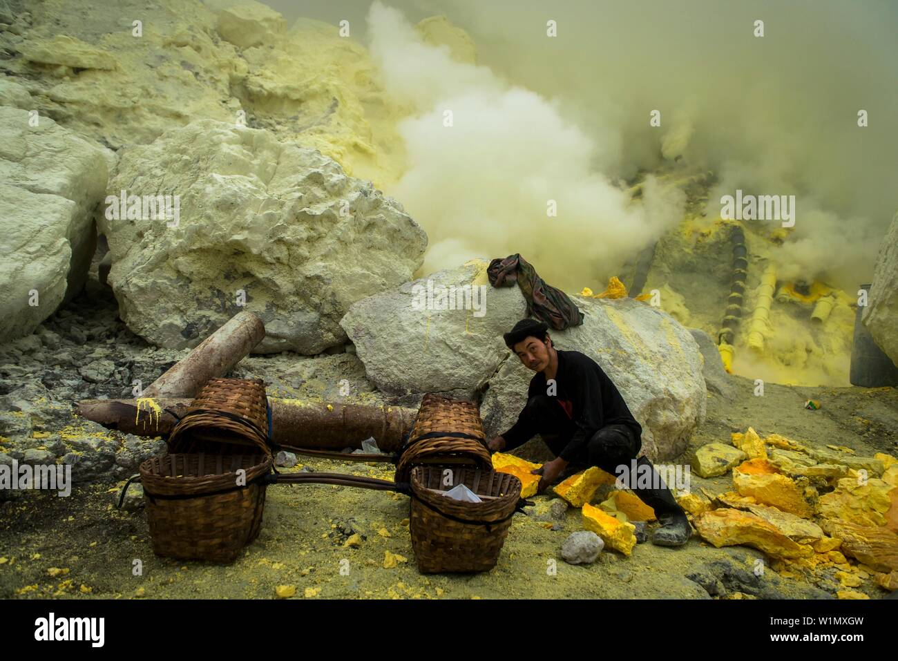 Minerworker zu giftiges Schwefeldioxid Gas der Mine ausgesetzt (Devil's mine) im Inneren des Vulkans Ijen auf der Insel Java und laden seine Körbe mit soliden Stockfoto