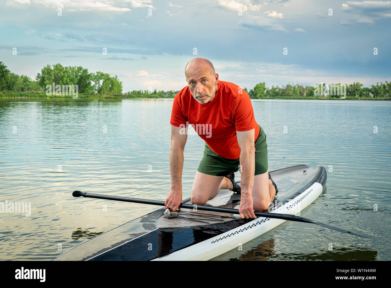 Umwelt Portrait eines älteren Paddler auf seinem Stand up paddleboard auf einem ruhigen See in Colorado. Stockfoto