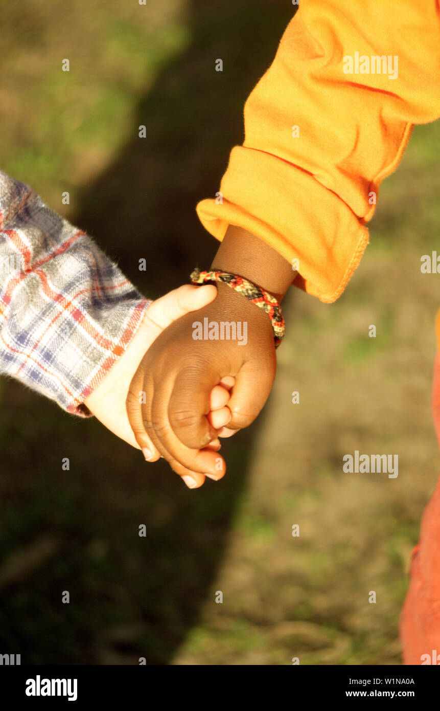 Weiße und schwarze Kind halten sich an den Händen, Menschen Stockfoto