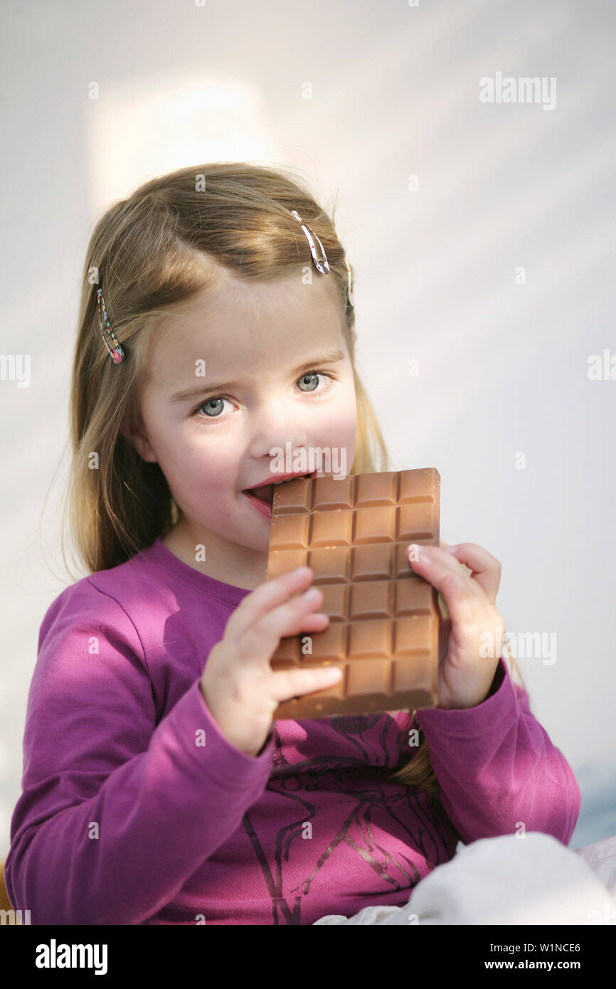 Mädchen (3-4 Jahre) eine Tafel Schokolade essen, München, Deutschland Stockfoto