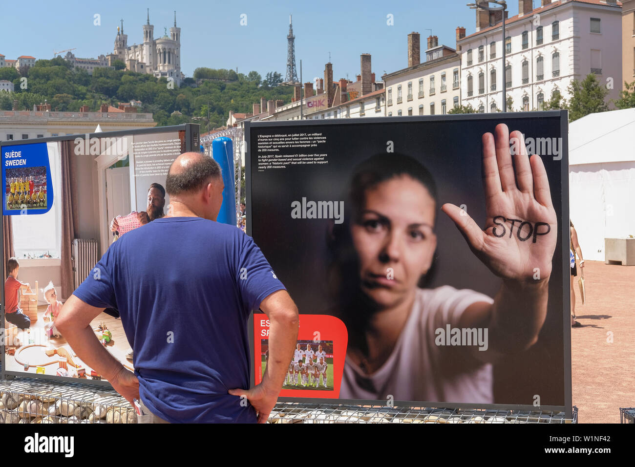 Fan Zone place Bellecour de Lyon ein Mann sieht eine Informationstafel über Gewalt gegen Frauen. Im Hintergrund die Basilika von Fourvière Stockfoto