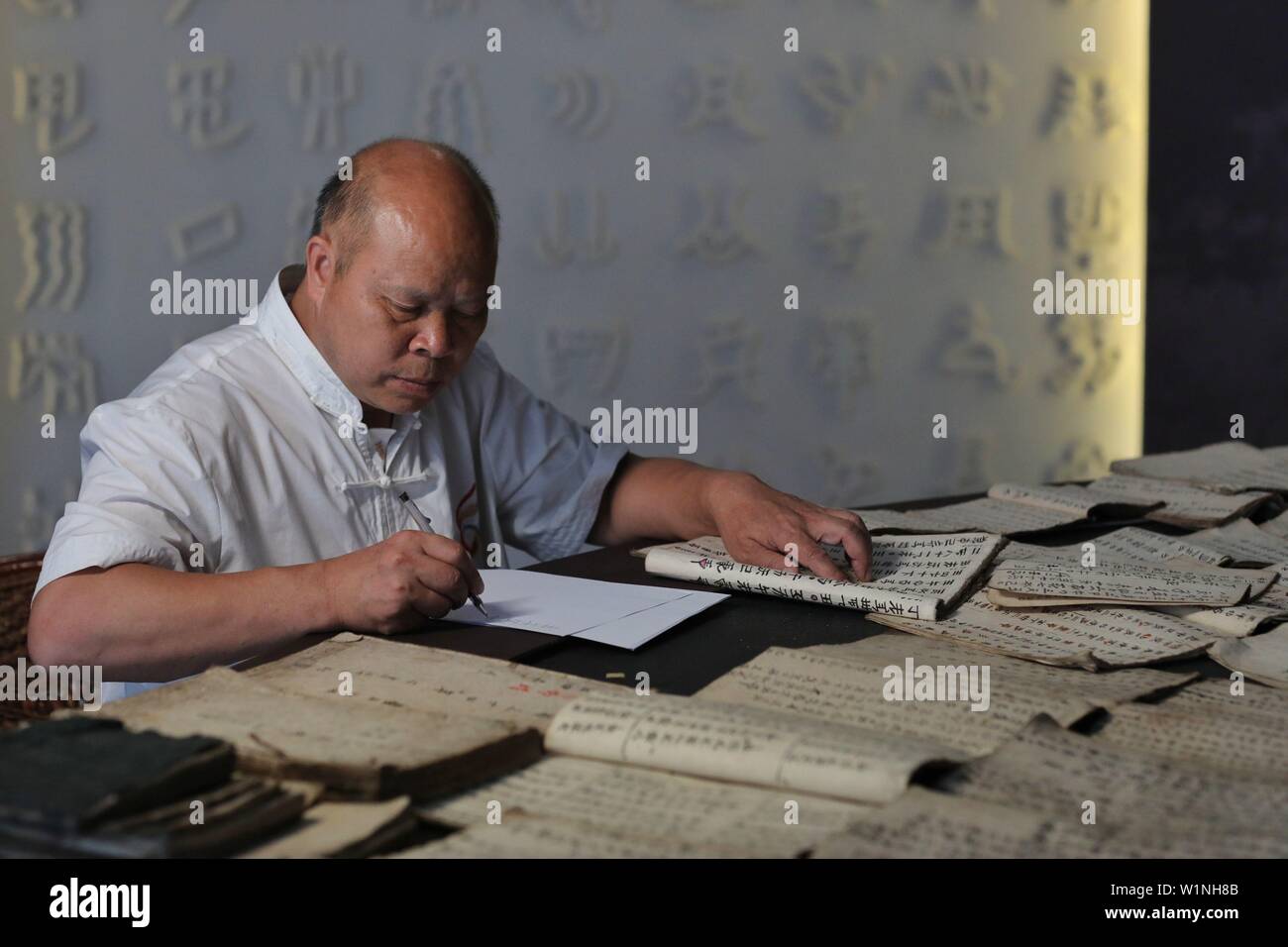 (190703) - SANDU, Juli 3, 2019 (Xinhua) - kulturwissenschaftler Wei Shizhao macht handschriftliche Kopien eines Textes in Shui Skript in Sandu County, im Südwesten Chinas Provinz Guizhou, 3. Juli 2019. Wei begann Shui Skript in seiner Kindheit. So weit, seine moderne chinesische Übersetzungen von Texten in Shui Skript haben, fast drei Millionen Zeichen betragen. Die Shui Skript ist der einzigartige Piktografische schreiben System durch die Shui Menschen im Südwesten Chinas verwendet, Aufzeichnungen über ihre Kultur halten. Inve wie die Bronze- und Oracle Knochen Inschriften des alten China, die Shui Skript besteht aus logograms Stockfoto
