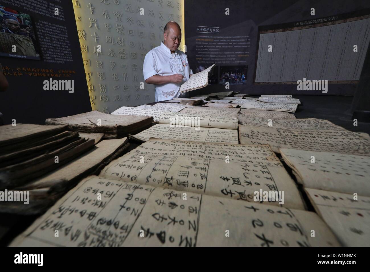 (190703) - SANDU, Juli 3, 2019 (Xinhua) - kulturwissenschaftler Wei Shizhao organisiert eine Sammlung von Texten in Shui Skript in Sandu County, im Südwesten Chinas Provinz Guizhou, 3. Juli 2019. Wei begann Shui Skript in seiner Kindheit. So weit, seine moderne chinesische Übersetzungen von Texten in Shui Skript haben, fast drei Millionen Zeichen betragen. Die Shui Skript ist der einzigartige Piktografische schreiben System durch die Shui Menschen im Südwesten Chinas verwendet, Aufzeichnungen über ihre Kultur halten. Invente wie die Bronze- und Oracle Knochen Inschriften des alten China, die Shui Skript besteht aus logograms Stockfoto