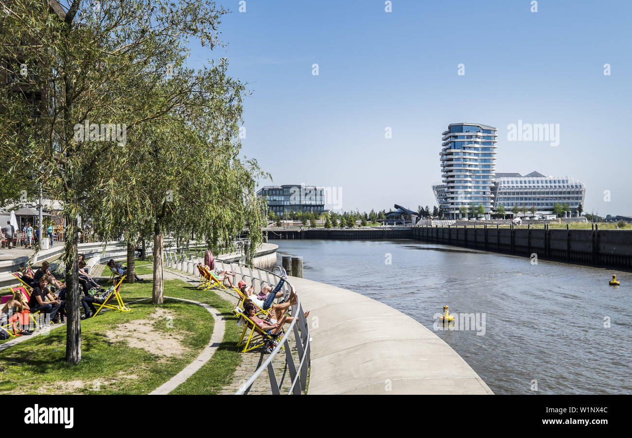 Leute sitzen am Dalmannkai mit Blick auf Marco Polo Tower in der Hafencity in Hamburg, Hamburg, Deutschland Stockfoto