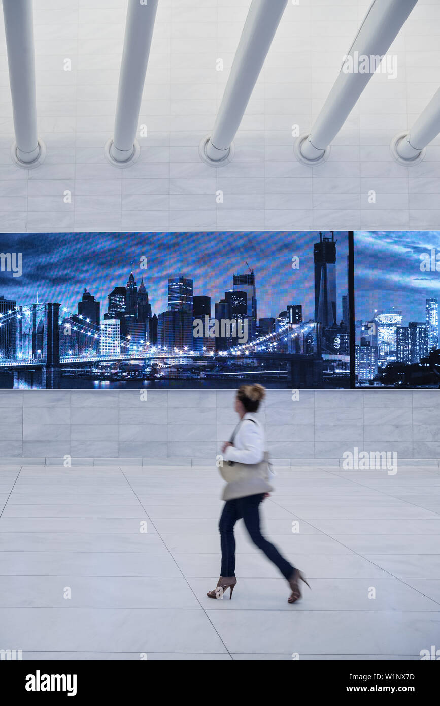 Frau, leuchtet eine Anzeige in einem Flur des Oculus und blickt auf die Skyline von New York, futuristischen Bahnhof von dem berühmten Architekten Santi Stockfoto