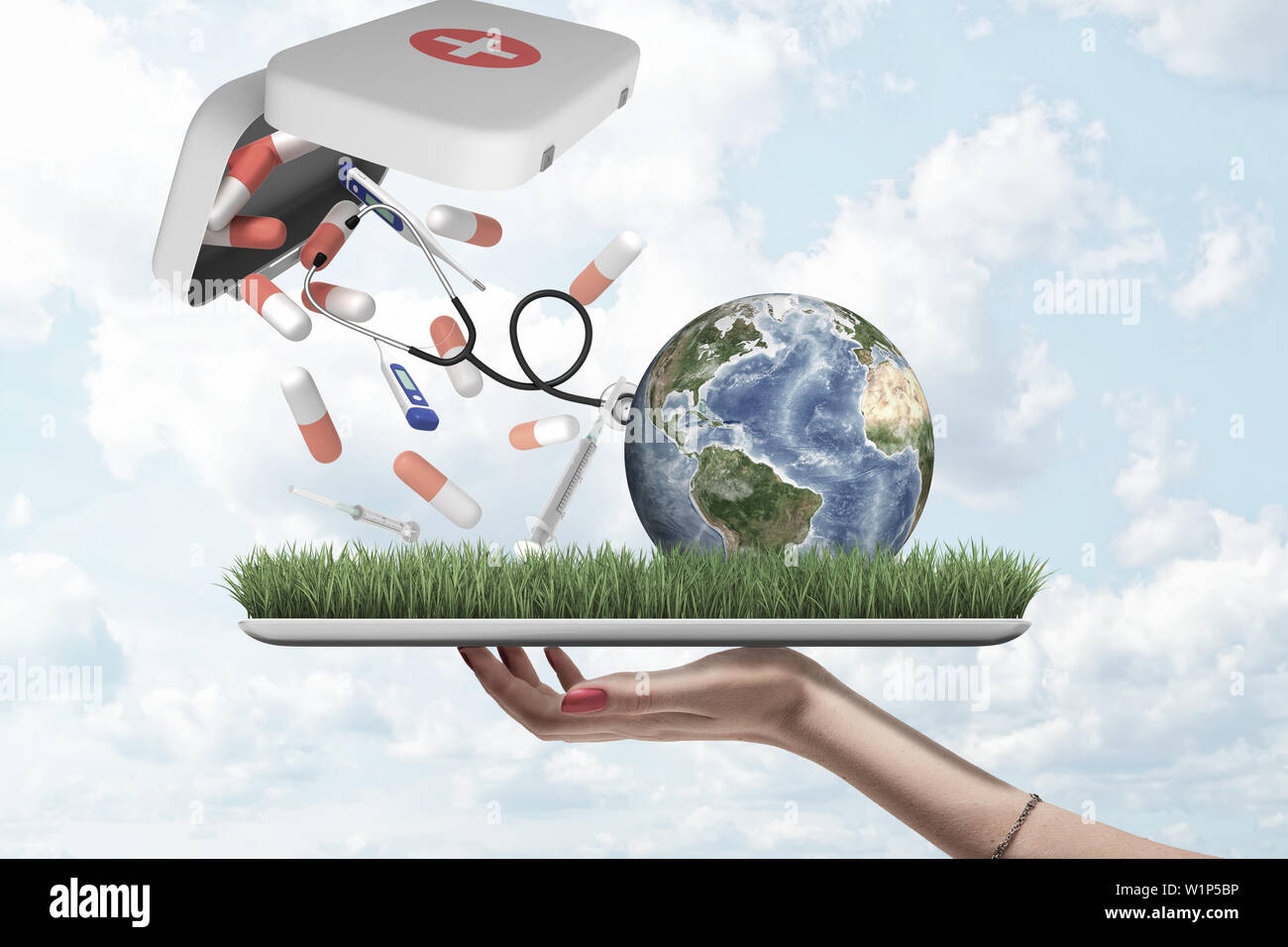 Weibliche Hand, die eine Erde Globus mit Pillen, Spritzen und digitale Thermometer fallen aus der ersten Hilfe Medical Kit auf grünem Gras Modell mit blauer Himmel Stockfoto