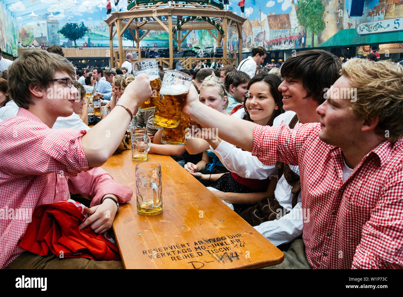 Nachtschwärmer heben ihre bierkrüge mit Toast auf dem Oktoberfest, München, Bayern, Deutschland Stockfoto