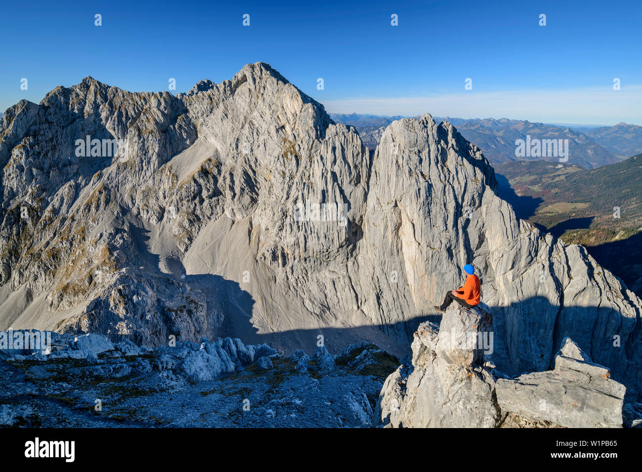 Mann sitzt auf Rock spire und Blick auf die Felswände des vorderen und hinteren Karlspitze, von der Hinteren Goinger Halt, Wilder Kaiser, Kaiser, Ty Stockfoto