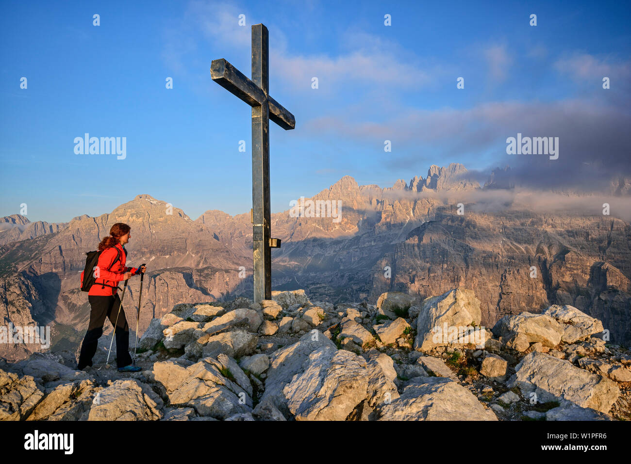 Frau wandern aufsteigender Richtung Kreuz auf dem Gipfel, Brenta Gruppe im Hintergrund, Croz dell'Altissimo, Brenta Gruppe, UNESCO Weltnaturerbe Dolomiten, Stockfoto