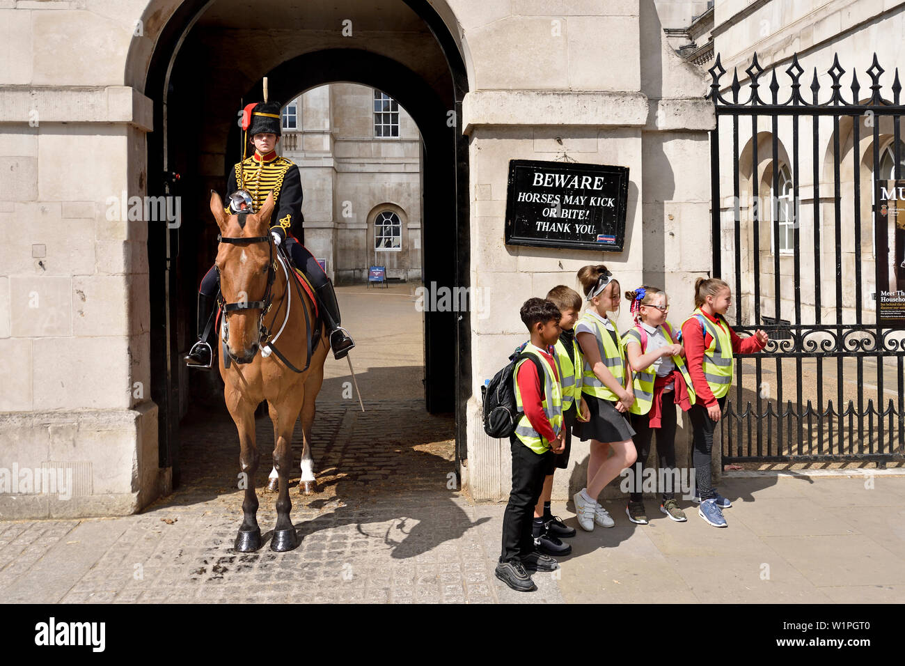 London, England, UK. Weibliche Mitglied des King's Troop, Royal Horse artillery, auf Aufgabe außerhalb der Horse Guards in Whitehall. Posi Gruppe von Schulkindern Stockfoto