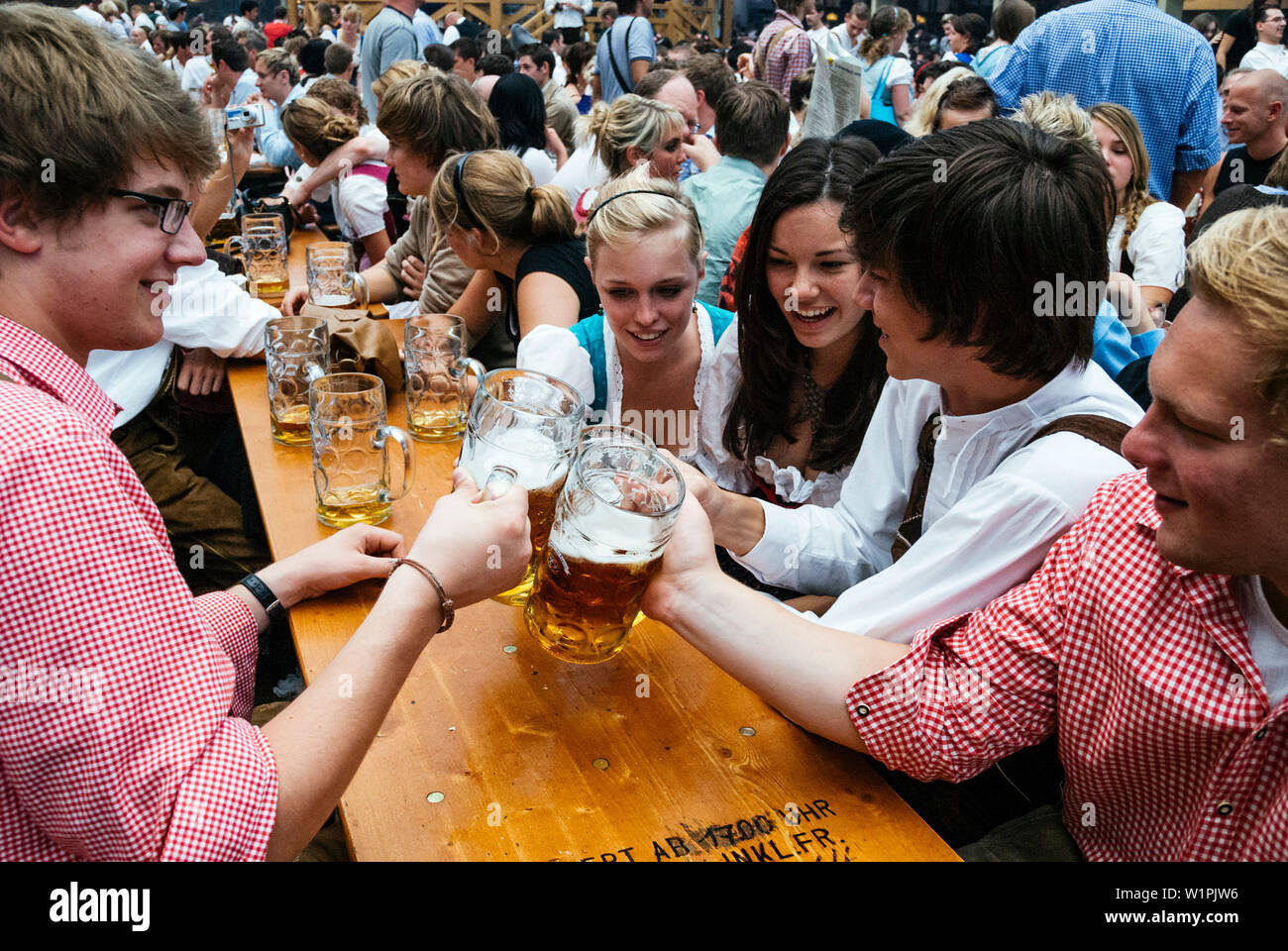 Nachtschwärmer heben ihre bierkrüge mit Toast auf dem Oktoberfest, München, Bayern, Deutschland Stockfoto