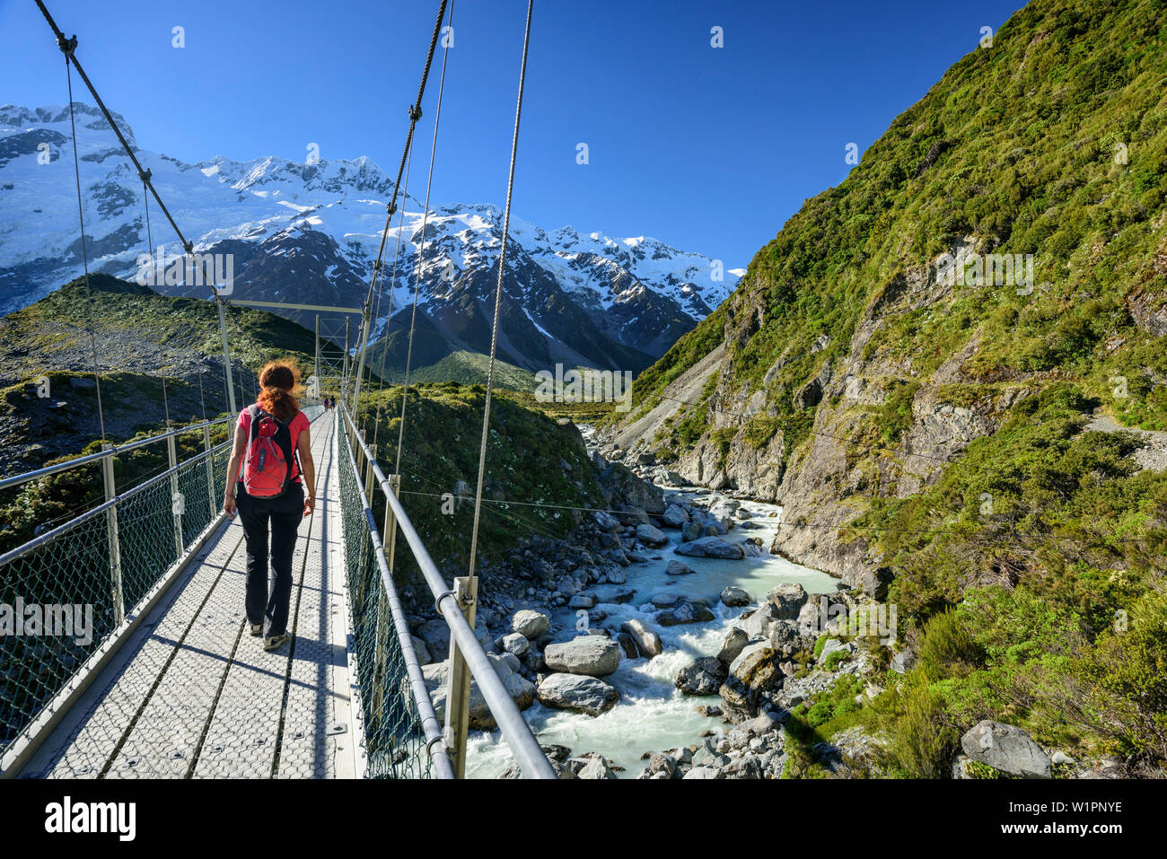 Frau Hooker River Crossing auf der Hängebrücke, Hooker Valley, Mount Cook, Mount Cook Nationalpark, UNESCO Welterbe Te Wahipounamu, Lake Pukaki, Ca Stockfoto