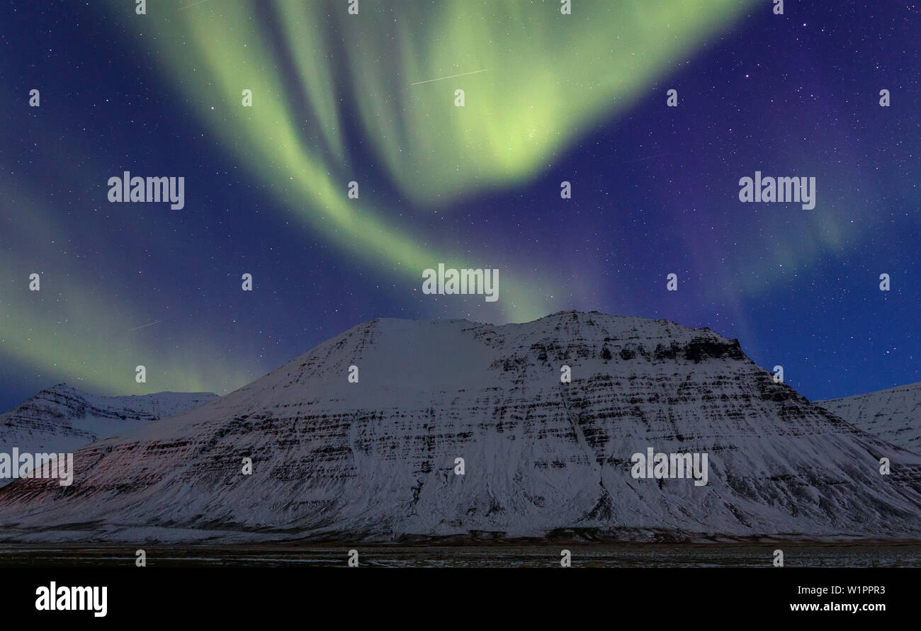 Polarlichter über einen schneebedeckten Berg in den Westfjorden, Island Stockfoto