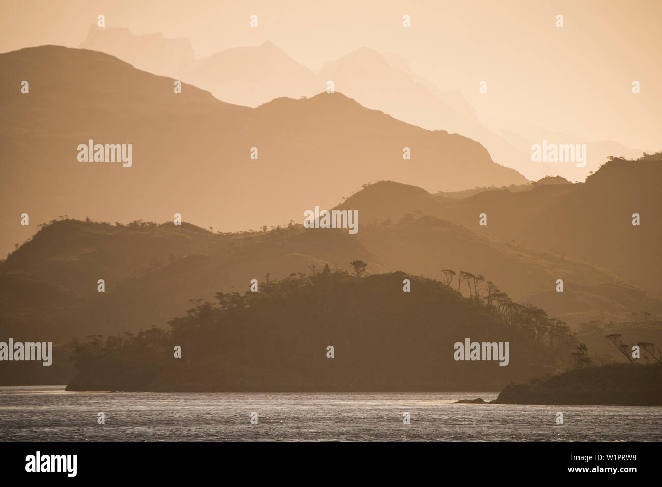 Am späten Nachmittag Sonne wirft eine rot-orange Glühen über Hügel und Berge, die in der Ferne gestapelt, Magellanstraße, Magallanes y de la Antarktis Chile Stockfoto