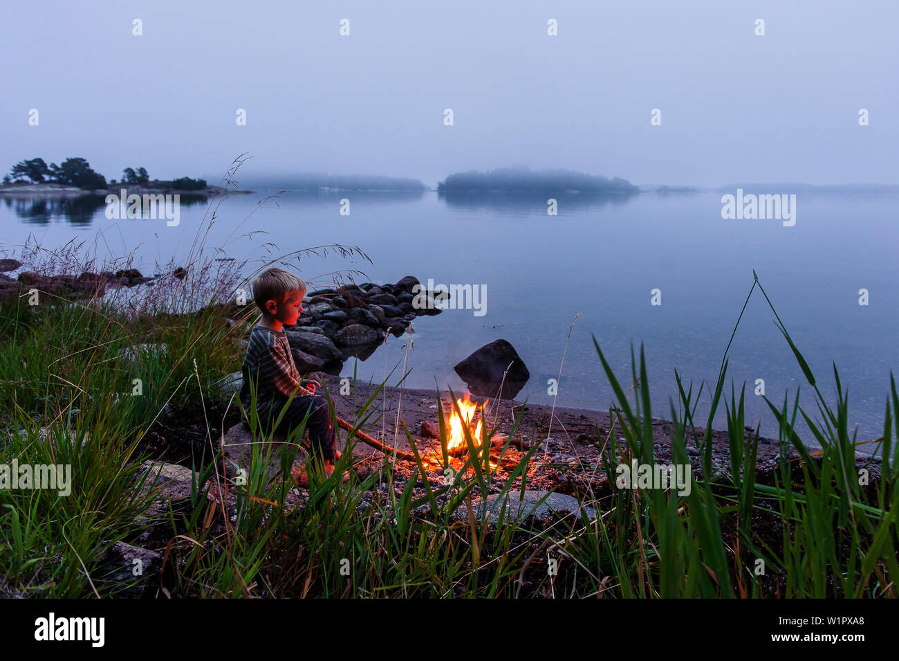 Kleiner Junge am Lagerfeuer im Archipel Insel Fiskhamn, Stockholm, Schweden Stockfoto