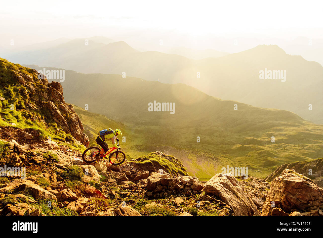 Im mittleren Alter Mountainbiker reitet ein technischer Weg auf einem felsigen Berghang in schönen, warmen Morgenlicht, Kirchberg, Tirol, Österreich Stockfoto