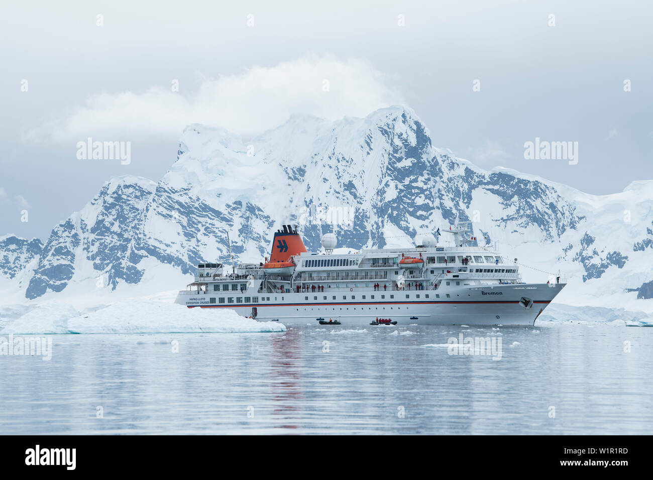 Expedition Kreuzfahrtschiff MS Bremen (Hapag-Lloyd Kreuzfahrten), unter  einem großen, schneebedeckten Berge gesehen, sendet Zodiac Beiboot Flöße  mit Passagieren auf einer Sc Stockfotografie - Alamy
