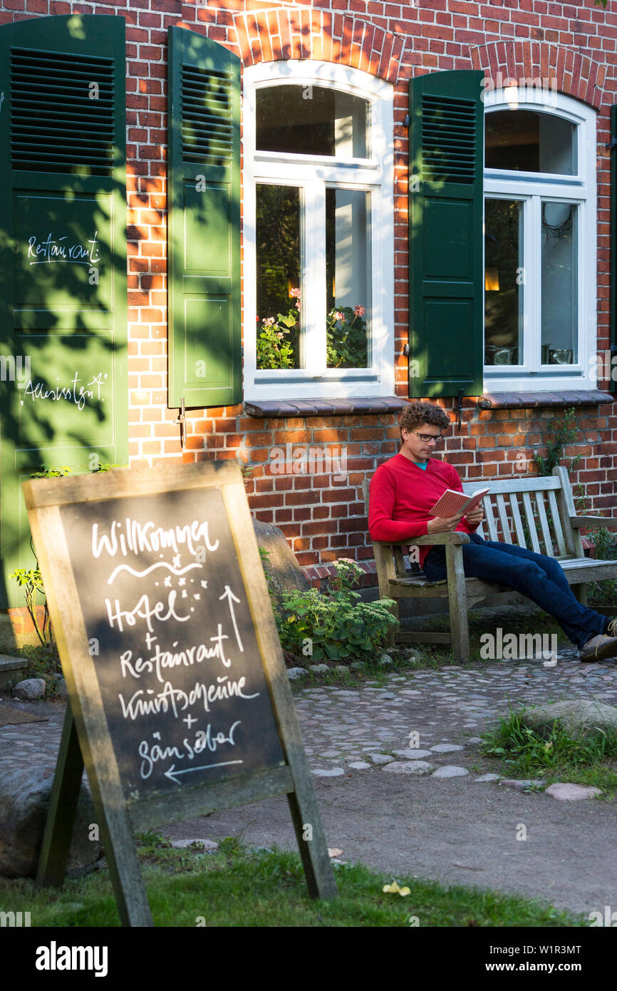 Mann auf der Bank, traditionellen Haus, Restaurant, See Hotel Neuklostersee, Urlaub, Mecklenburgische Seenplatte, Mecklenburger Seenplatte, Neukloster, Mecklenburg- Stockfoto
