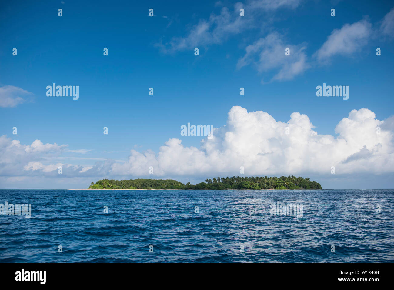Ein langer, tiefer liegende Insel liegt im tiefen blauen Meer unter einem Himmel von großen weißen Wolken dominiert, Jabor Insel, Atoll, Jaluit Ralik Kette, Marshall Inseln, Stockfoto
