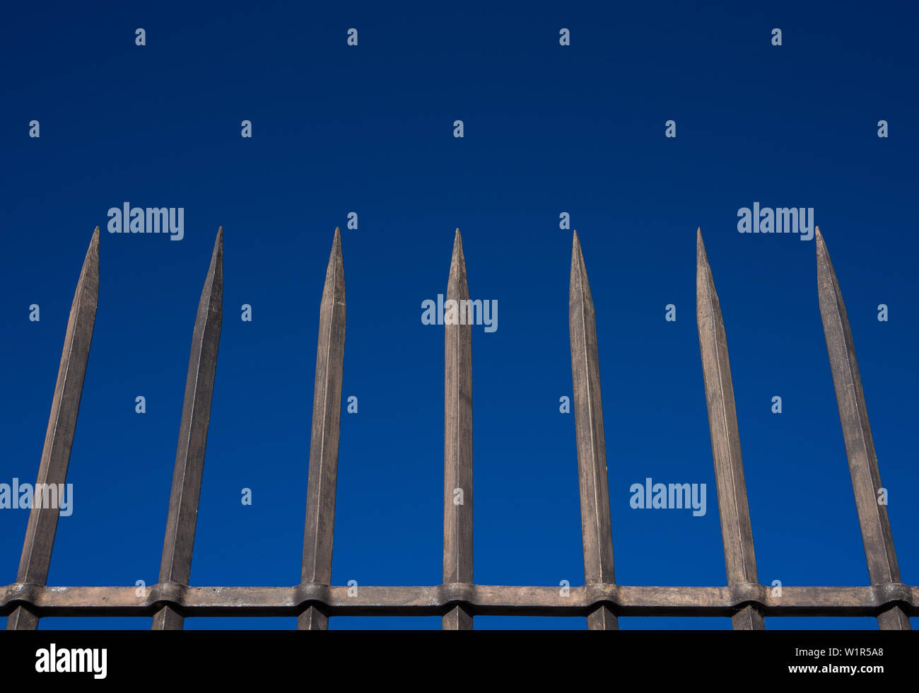 Stahl zaun Barriere mit spitzen Bars gegen den blauen Himmel. Konzept der Einsamkeit hineingetrieben, Hindernis, hier finden sie Schutz Stockfoto