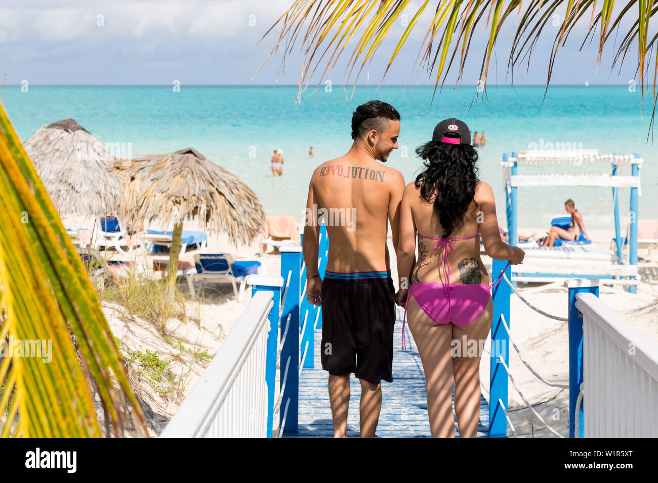 Kubanisches zu Fuß zum Strand, Tattoo auf dem Rücken: revolucion, Symbol der Kuba, Touristen zu den schönsten Strand in Cayo Guillermo, Playa Pil Stockfoto